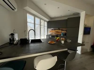 a kitchen with a counter with a sink and some chairs at Studio confortable proche mer deb1890 in Cannes