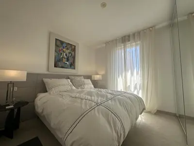 a white bedroom with a bed and a window at Appartement centre ville 7 Lecerf in Cannes