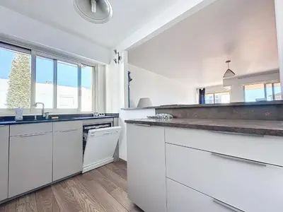 a kitchen with white cabinets and a large window at 78m2 Terrasse vue mer à 50m de la Croisette in Cannes
