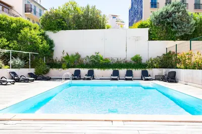 a swimming pool with chairs in a courtyard at Cosy Escape YourHostHelper in Cannes