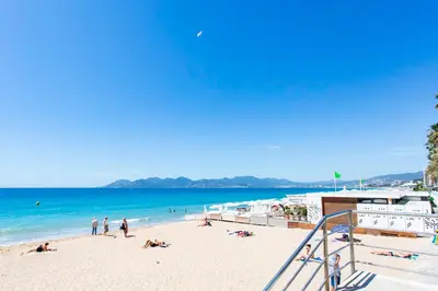a beach with people laying on the sand and the ocean at Cosy Escape YourHostHelper in Cannes