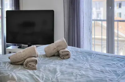 a bedroom with a tv and towels on a bed at Le Eve- 350M mer- 600 Palais-VCA in Cannes