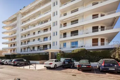 a large white building with cars parked in a parking lot at ARM1 - Beau 2 pièces avec terrasse d'angle in Cannes