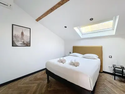 a bedroom with a large white bed with a skylight at 140m2 vue mer, 3 chambres, centre-ville in Cannes