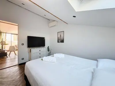 a white bedroom with two beds and a television at 140m2 vue mer, 3 chambres, centre-ville in Cannes