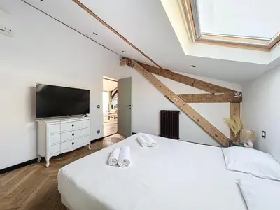 a white bedroom with a large bed and a television at 140m2 vue mer, 3 chambres, centre-ville in Cannes