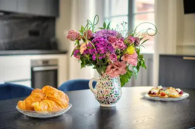 a vase of flowers sitting on a table with bread at Marigold - 2 Bed 2 bath - AC - 8 min from Palais in Cannes
