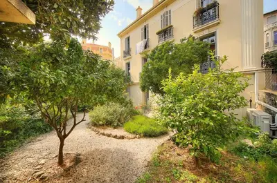 a garden with trees and bushes in front of a building at Marigold - 2 Bed 2 bath - AC - 8 min from Palais in Cannes