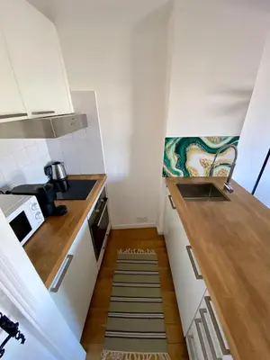 a small kitchen with white cabinets and a wooden floor at Appartamento coeur du Suquet in Cannes