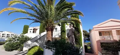 a statue of a man standing next to a palm tree at Le Paradis d'Ella in Cannes