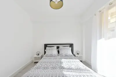 a white bedroom with two beds and a clock on the wall at Apartment with Terrace walk to Beaches & Shopping in Cannes