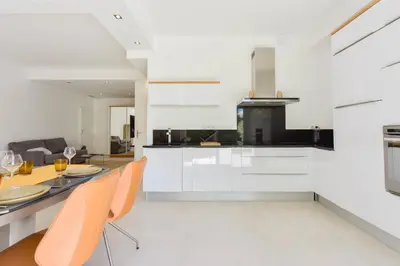 a kitchen with white cabinets and a table and chairs at 1-bedroom apartment walk to beach garage in Cannes