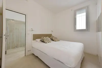 a white bedroom with a bed and a mirror at 1-bedroom apartment walk to beach garage in Cannes