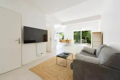 a white living room with a couch and a tv at 1-bedroom apartment walk to beach garage in Cannes