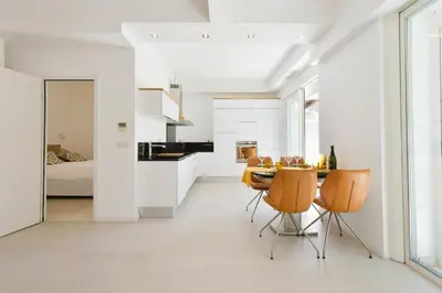 a kitchen and dining room with white walls and a table and chairs at 1-bedroom apartment walk to beach garage in Cannes