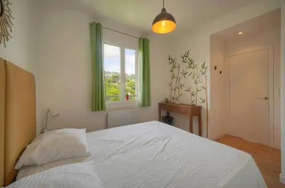 a bedroom with a bed and a window with green curtains at FRGK Isola Bella ' Appartement Confortable' in Cannes