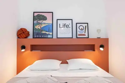 a headboard of a bed with three pictures above it at 2 pièces cosy en centre ville in Cannes
