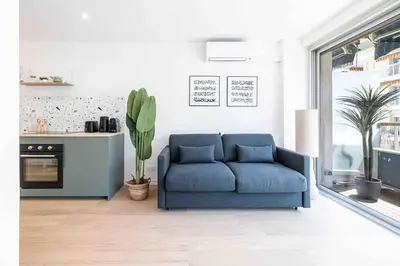 a living room with a blue couch and a kitchen at 2 pièces cosy en centre ville in Cannes