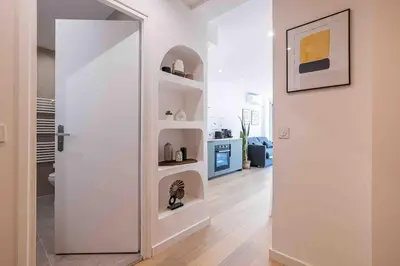 a room with white walls and a door with shelves at 2 pièces cosy en centre ville in Cannes