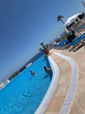 two people swimming in a swimming pool at a resort at Villa Francia Résidence piscine tennis à 500m des plages de Cannes in Cannes