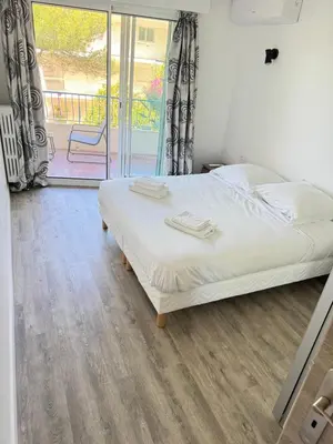 a bedroom with a bed with white sheets and a window at Appartement vue mer, Long Beach in Cannes