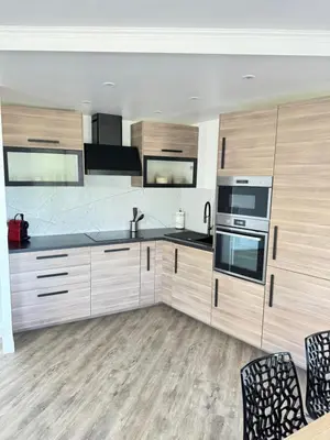 a kitchen with wooden cabinets and black counter tops at Appartement vue mer, Long Beach in Cannes