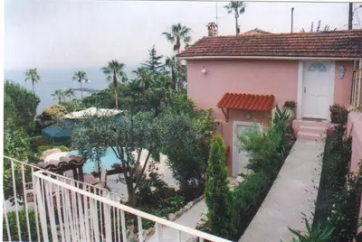 a pink house with a white door and palm trees at Maison Louijane in Vallauris