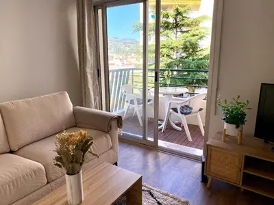 a living room with a couch and a table and a balcony at Appartement à 10min à pied Palais Festivals in Cannes