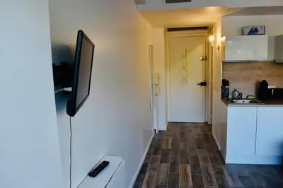 a kitchen with white cabinets and a television on the wall at Studio bord de mer in Cannes