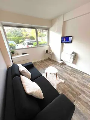 a living room with a black couch and a window at Studio bord de mer in Cannes