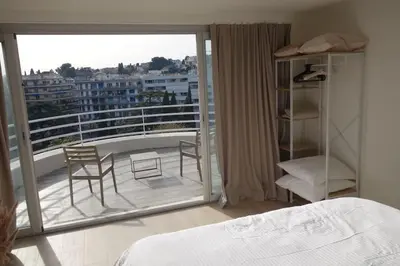 a bedroom with a balcony with two chairs and a bed at Studio Toit terrasse - Vue mer Cannes in Le Cannet