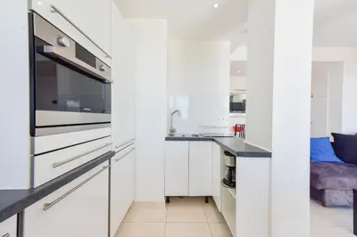 a kitchen with white cabinets and a sink at Cozy top-floor 2-Br apartment terrace and sea view in Cannes