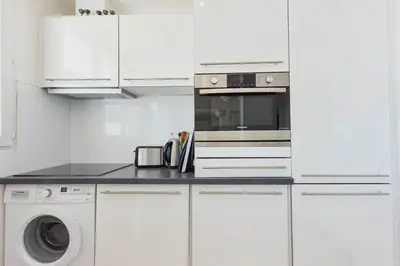 a white kitchen with a washer and dryer at Cozy top-floor 2-Br apartment terrace and sea view in Cannes