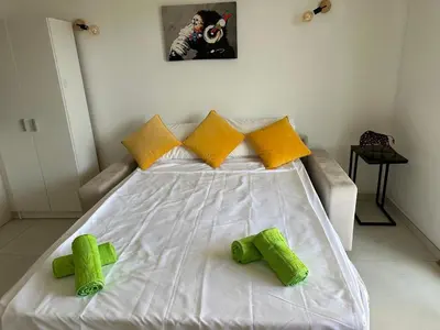 a large white bed with yellow and green pillows at Super Apartment, Parking, Terrace, Lift, WIFI, Palm Beach, Cannes in Cannes