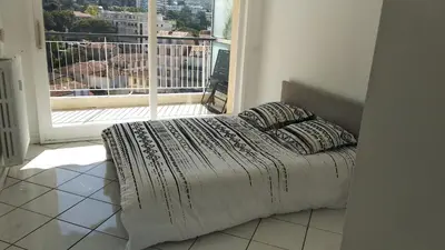 a bed in a room with a large window at Beau 2 pièces centre de Cannes idéal congres et vacances in Cannes