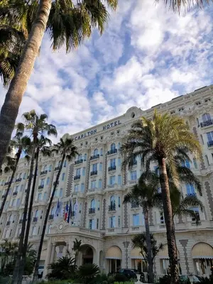 a hotel with palm trees in front of it at Chambre cosy dans T3 in Cannes