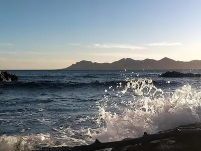 a wave in the ocean with mountains in the background at Chambre cosy dans T3 in Cannes