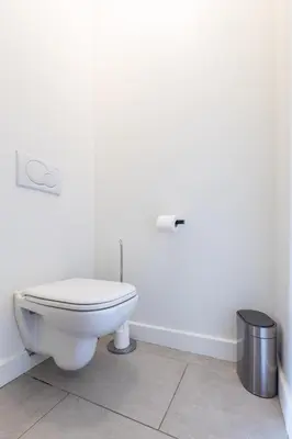 a white bathroom with a toilet and a trash can at LB Vacation Rentals I Beautiful, Renovated Duplex with Swimming Pool in Cannes