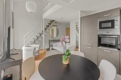 a dining room with a black table and chairs at LB Vacation Rentals I Beautiful, Renovated Duplex with Swimming Pool in Cannes