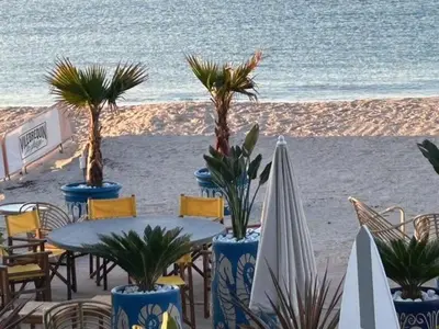 a table and chairs on the beach with palm trees at Elegant studio a 50m de la Croisette et ses plages - Ada Serenity Beach in Cannes