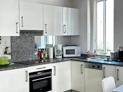 a white kitchen with white cabinets and a microwave at Elegant studio a 50m de la Croisette et ses plages - Ada Serenity Beach in Cannes