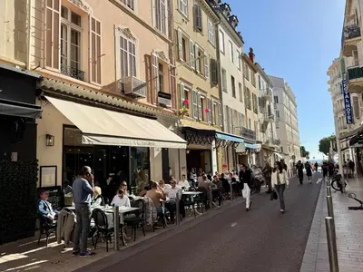 a group of people sitting at tables in a street at A006 Superbe Appartement dans le Carre d'Or-Cannes in Cannes