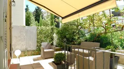 an outdoor patio with chairs and an umbrella at Maison CENTRE CANNES 2 CHAMBRES 4 COUCHAGES in Cannes