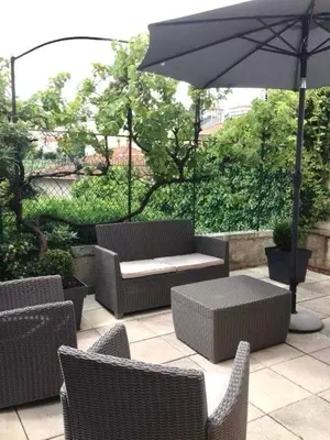 a patio with wicker chairs and a table and an umbrella at Maison CENTRE CANNES 2 CHAMBRES 4 COUCHAGES in Cannes