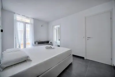 a white bedroom with a large bed and a window at Design 2 pièces CARRE D'OR -COEUR DE CANNES A1B205 in Cannes