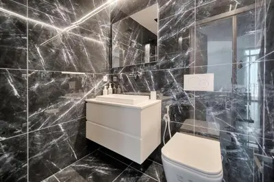 a black tiled bathroom with a toilet and a sink at Design 2 pièces CARRE D'OR -COEUR DE CANNES A1B205 in Cannes