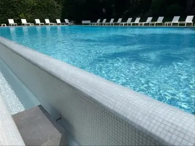 a swimming pool with chairs and blue water at Cocon paradisiaque avec piscine, terrasse, jardin au calme absolu in Cannes
