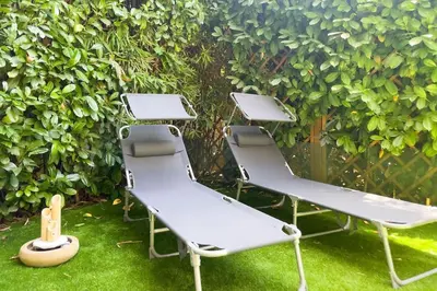 three picnic chairs sitting in the grass in front of a hedge at Cocon paradisiaque avec piscine, terrasse, jardin au calme absolu in Cannes
