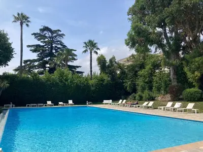 a large swimming pool with chairs and palm trees at Cocon paradisiaque avec piscine, terrasse, jardin au calme absolu in Cannes