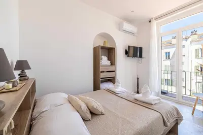 a white bedroom with two beds and a window at Cozy One Bedroom apartment - heart of Cannes in Cannes